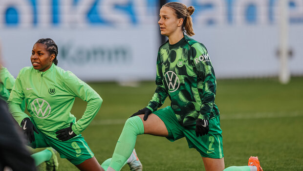 VfL-Wolfsburg-Spielerin Lynn Wilms macht im Ausfallschritt eine Dehnübung.