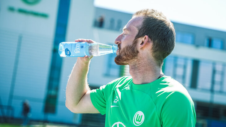 Der VfL Wolfsburg-Spieler Maximilian Arnold trinkt aus einer Wasserflasche.