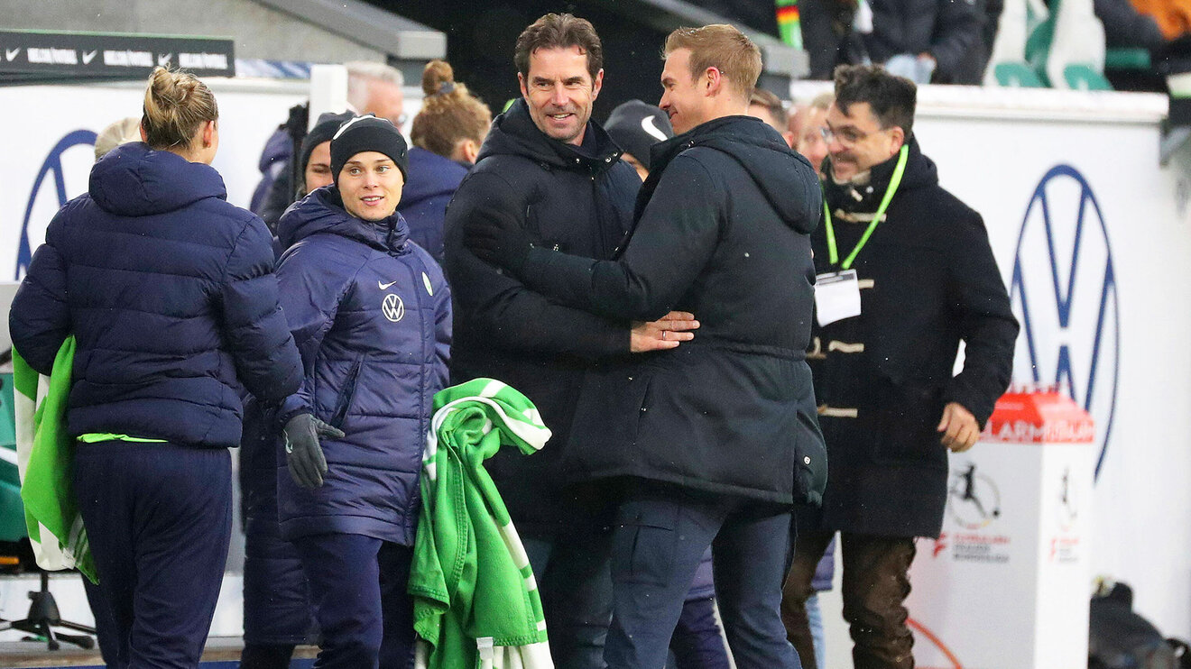 Der sportliche Leiter, Ralf Kellermann, freut sich mit dem VfL-Wolfsburg-Trainer Tommy Stroot am Spielfeldrand.