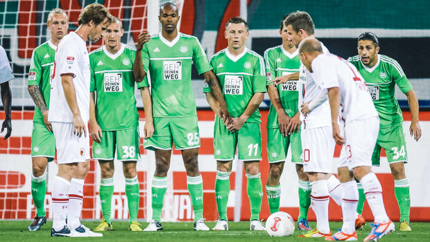 Historisches Foto von VfL Wolfsburg Spielern, die in einem Spiel gegen Augsburg vor dem Tor eine Mauer bilden.