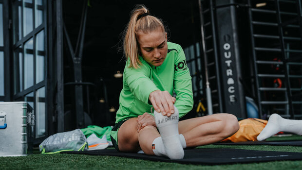 Die VfL-Wolfsburg-Spielerin Janina Minge dehnt sich.