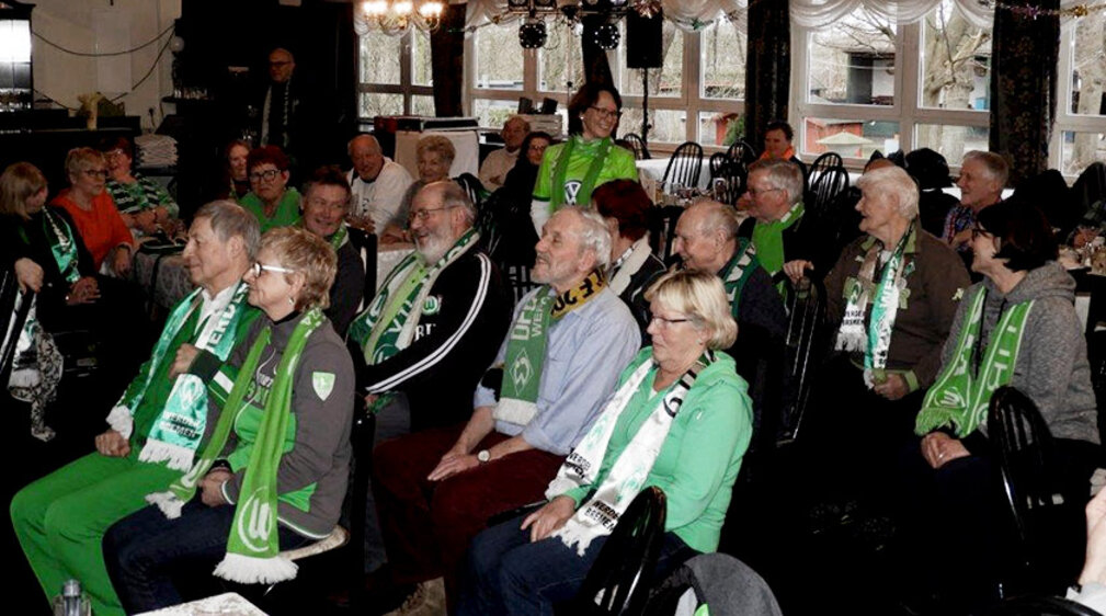 Die Mitglieder des WölfeClubs 55plus des VfL Wolfsburg sitzen in einem Saal.