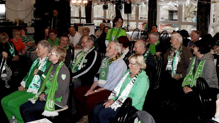Die Mitglieder des WölfeClubs 55plus des VfL Wolfsburg sitzen in einem Saal.