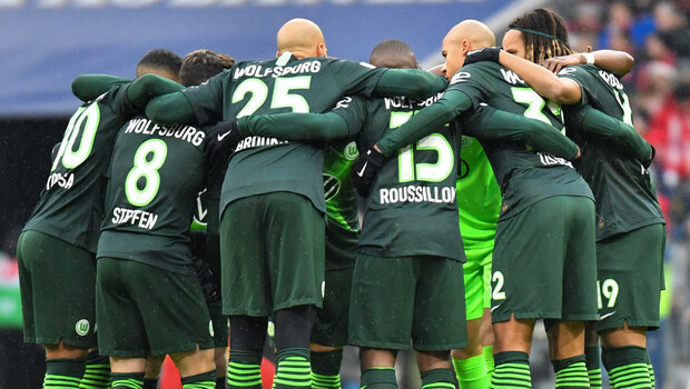 VfL Wolfsburg Spieler formen einen Kreis auf dem Spielfeld vor dem Anpfiff der Partie gegen Bayern München.