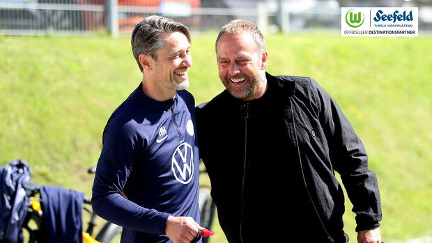 Der VfL Wolfsburg-Trainer Niko Kovac steht lachend mit Hansi Flick am Spielfeldrand.