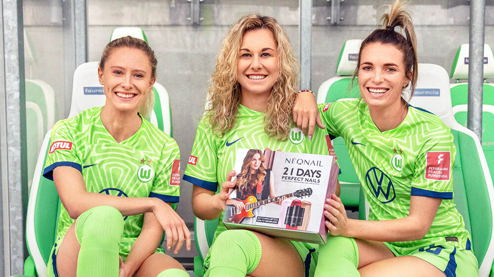 Drei VfL Wolfsburg Spielerinnen posieren mit einem Neonail Paket.