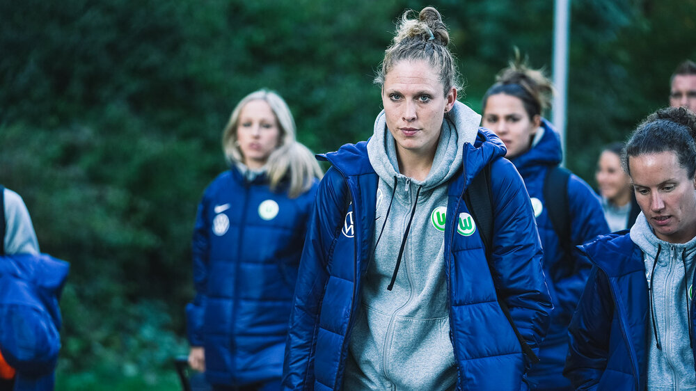Kim Kulig, Co-Trainerin der VfL-Wolfsburg-Frauen, geht inmitten anderer Trainerinnen und Spielerinnen.