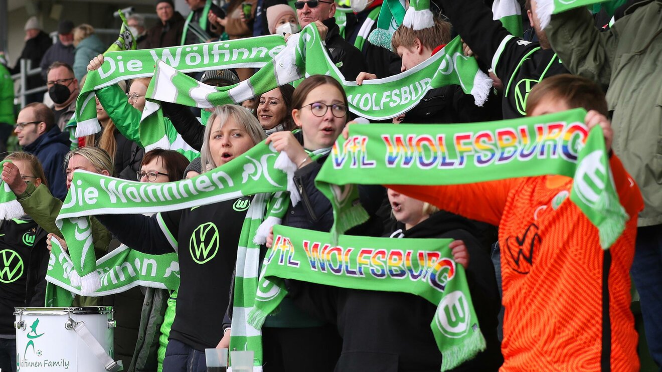 VfL Wolfsburg-Fans halten ihre Schals nach oben.