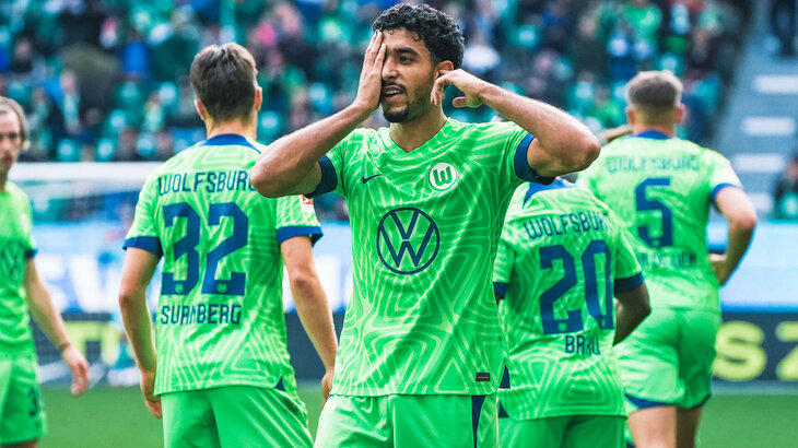 Omar Marmoush vom VfL Wolfsburg hält die rechte Hand ins Gesicht.