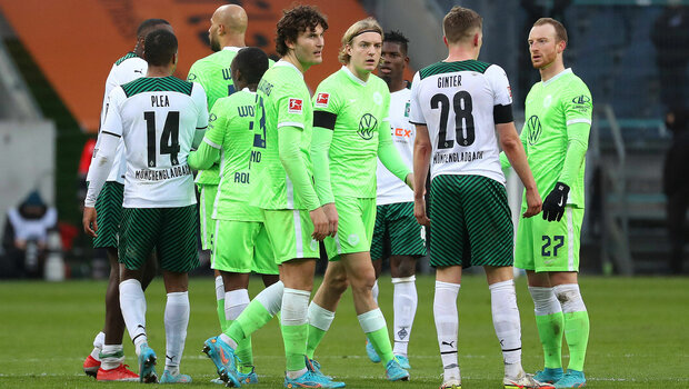Mehrere Spieler vom VfL-Wolfsburg und von Gladbach stehen auf dem Platz zusammen. 