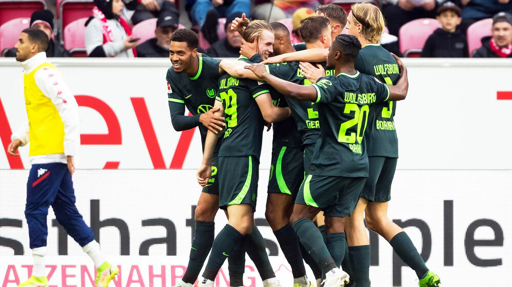 Die Männer des VfL Wolfsburg jubeln gemeinsam auf dem Spielfeld.