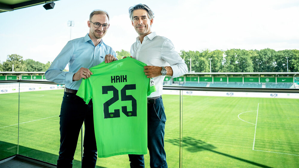 Michael Meeske vom VfL Wolfsburg hält mit dem Sponsoringverantwortlichen von Haix das Trikot.