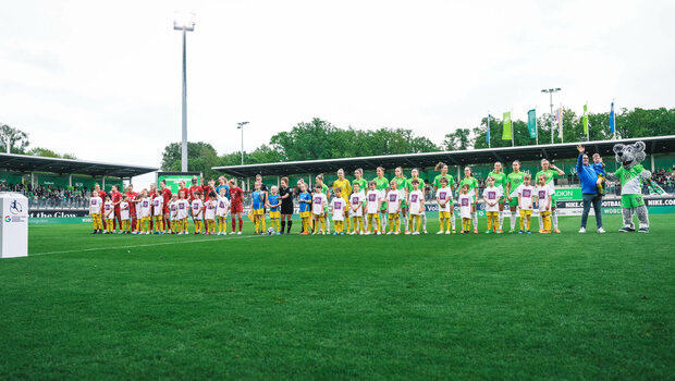 Die Teams vom VfL Wolfsburg und Köln stehen nach dem Einlaufen auf dem Platz.