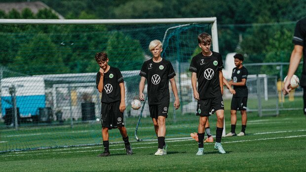 Nachwuchsspieler des VfL Wolfsburg trainieren auf dem Trainingsplatz und warten auf Anweisungen.