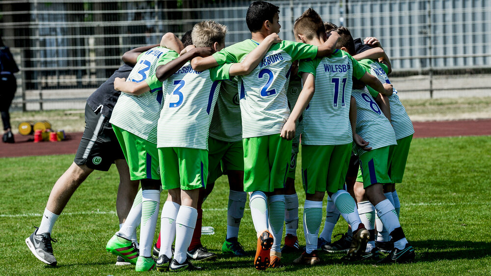 Nachwuchsspieler des VfL Wolfsburg bilden einen Kreis.