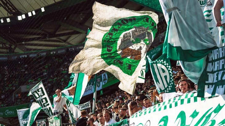 Die VfL-Wolfsburg-Fans wedeln mit ihren grün-weißen Fahnen.