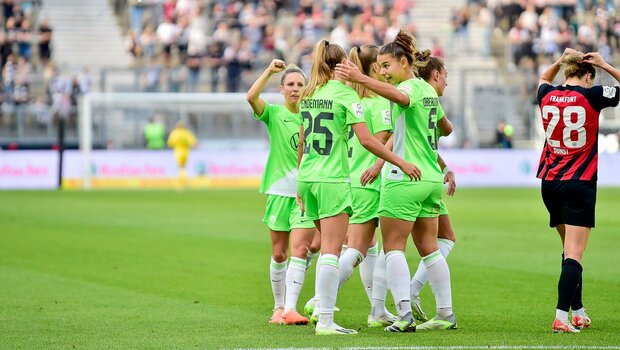 Die VfL Wolfsburg Spielerinnen jubeln sich umarmend auf dem Spielfeld.