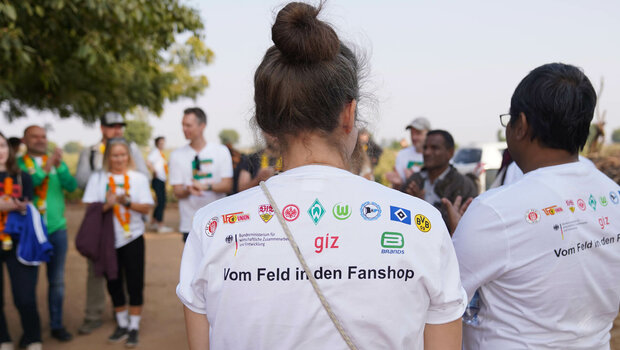 Eine Frau trägt ein Shirt mit den Logos von Bundesligavereinen.