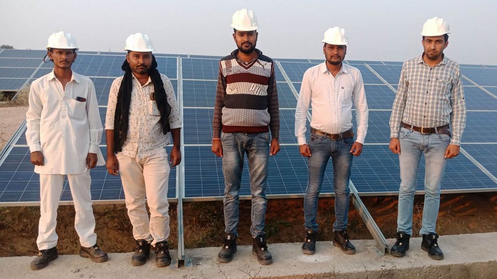 Inidische Arbeiter vor einer Solaranlage.