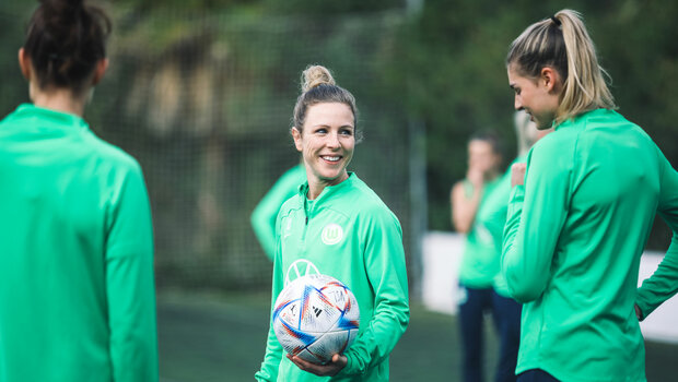 Die VfL-Wolfsburg-Spielerin Svenja Huth steht lachend mit dem Ball in der Hand auf dem Platz.