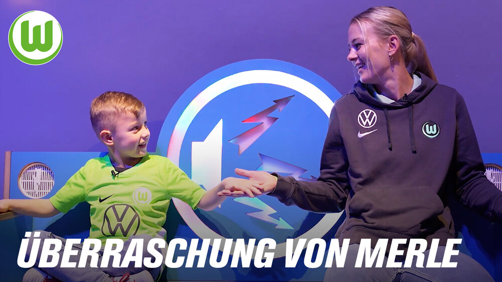 Merle Frohms hält die Hand eines kleinen Jungen in VfL-Wolfsburg-Trikot.