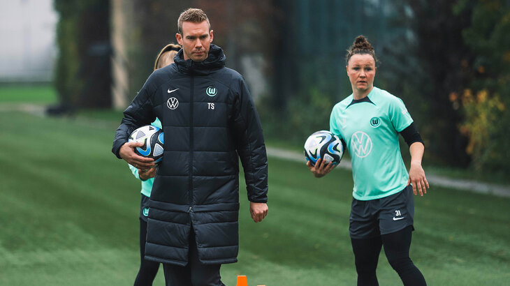 VfL-Wolfsburg-Trainer der Frauen Tommy Stroot steht auf dem Trainingplatz und hält einen Ball.