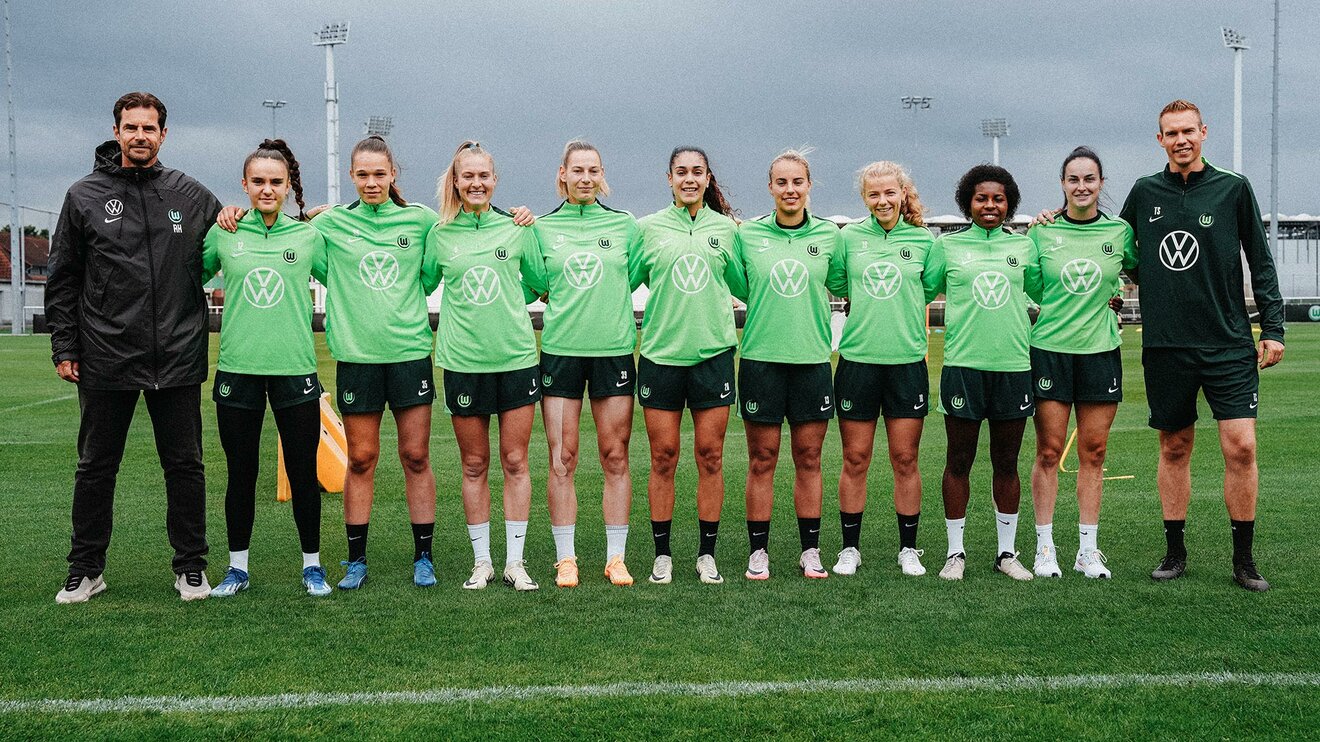 Ralf Kellermann und Tommy Stroot stehen in einer Reihe mit den neuen Spielerinnen des VfL Wolfsburg zur Saison 24/25.