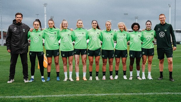 Ralf Kellermann und Tommy Stroot stehen in einer Reihe mit den neuen Spielerinnen des VfL Wolfsburg zur Saison 24/25.