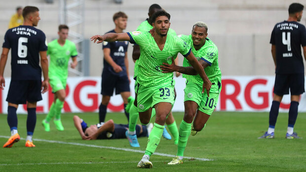 Omar Marmoush wird von seinem Mitspieler Lukas Nmecha mit viel Freude umarmt für den gelungenen Abschluss im Spiel Jena vs. VfL Wolfsburg.