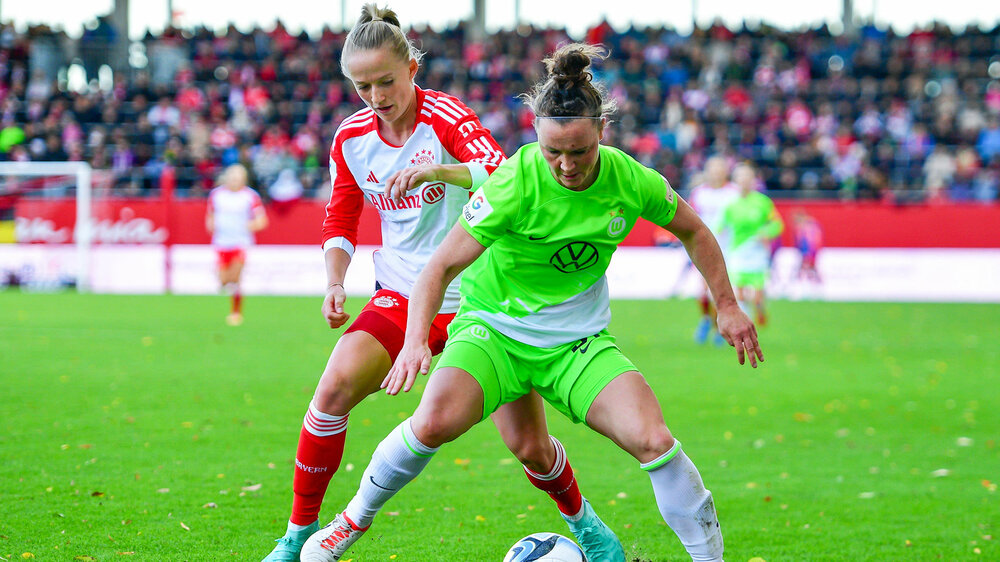Marina Hegering vom VfL Wolfsburg dreht der Gegnerin den Rücken zu und schaut zum Ball.