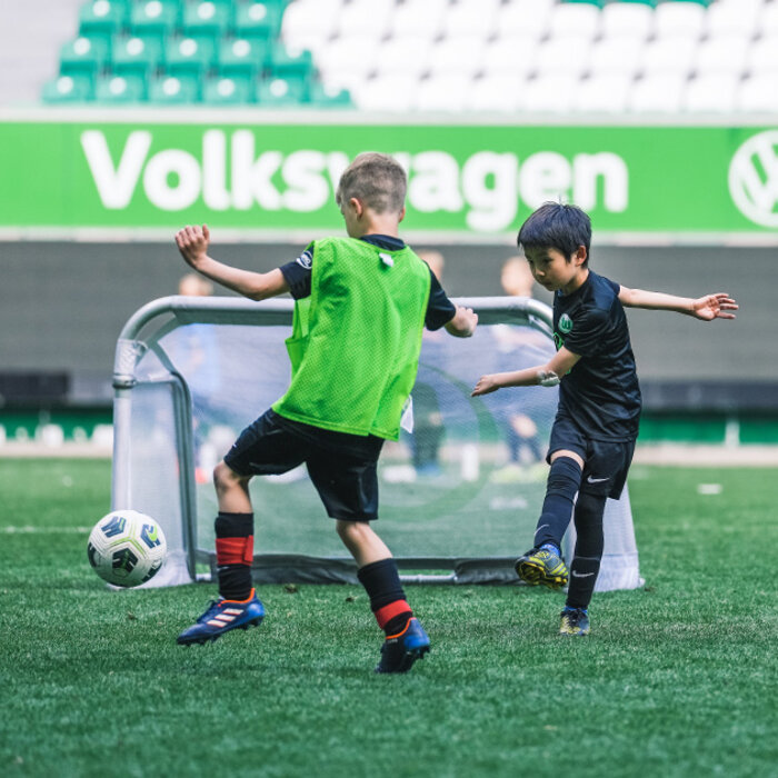 Kinder spielen in der Volkswagenarena des VfL Wolfsburg Fußball.