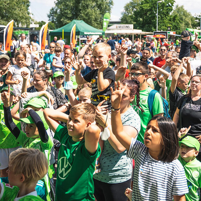Junge Fans zusammen mit ihren Eltern vor der Aktionsbühne auf der Fanmeile vor der Volkswagen Arena des VfL Wolfsburg. 