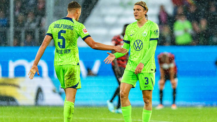 Die VfL-Wolfsburg-Spieler Micky van de Ven und Sebastiaan Bornauw schlagen auf dem Spielfeld ein.