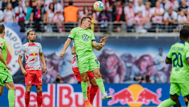 Die Spieler des VfL Wolfsburg und Max Kruse springen für einen Kopfball in die Höhe.