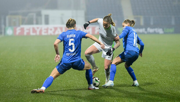 Linn Wilms vom VfL-Wolfsburg ist mit dem rechten Fuß am Ball.Von links versucht Jamilla Sofia Rankin und von rechts Dominika Grabowska (beides ihre Gegenspielerinnen) den Ball für sich zu gewinnen. 