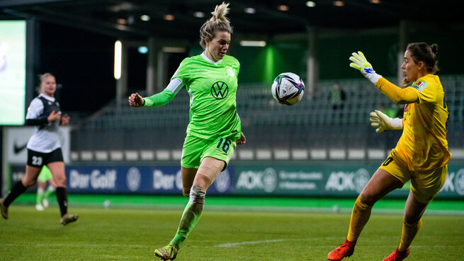 Sandra Starke nimmt den fliegenden Ball mit dem Oberkörper an, vor ihr steht die gegnerische Torwärtin im Spiel des VfL Wolfsburg gegen Sand.