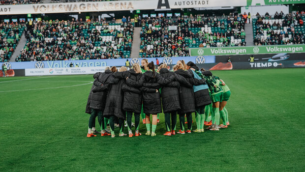 Die VfL-Wolfsburg-Spielerinnen stehen in einem Kreis zusammen.