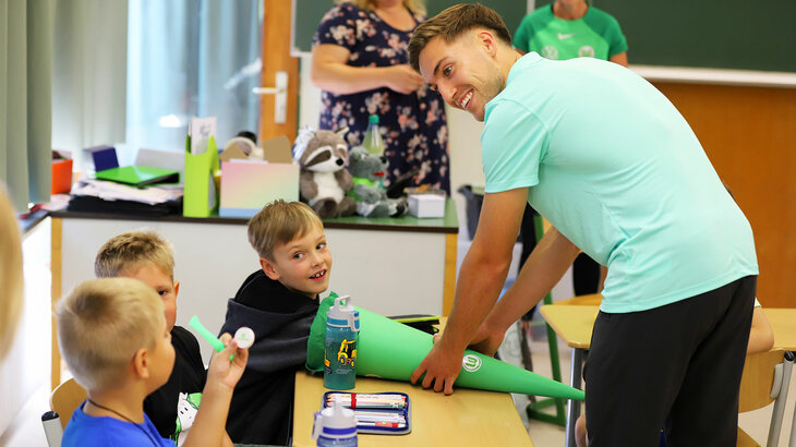 Kilian Fischer vom VfL Wolfsburg übergibt den Kindern eine Schultüte.