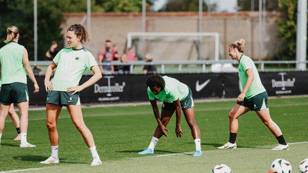 Die Spielerinnen des VfL Wolfsburg dehnen sich gemeinsam im Training.