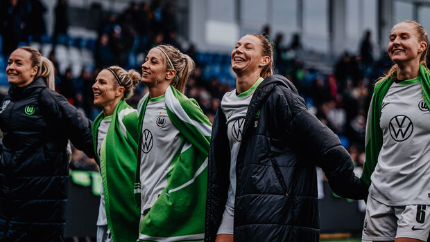 VfL-Wolfsburg-Spielerin Kathy Hendrich steht Hand in Hand mit weiteren Mitspielerinnen.