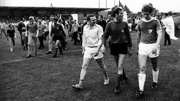 Ein historisches schwarz-weiß-Foto vom einlaufen der Spieler vor einem Spiel des VfL Wolfsburg gegen VfL Bochum.