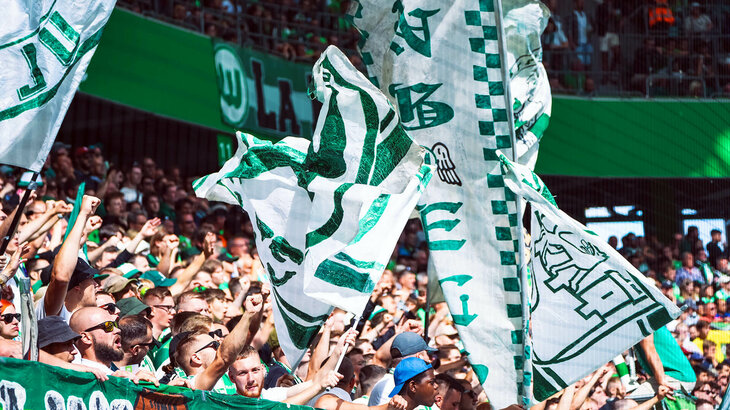 Die Fans des VfL Wolfsburg schwenken ihre Fahnen.