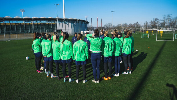 Das Team der Frauen vom VfL Wolfsburg steht im Kreis auf dem Trainingsplatz.