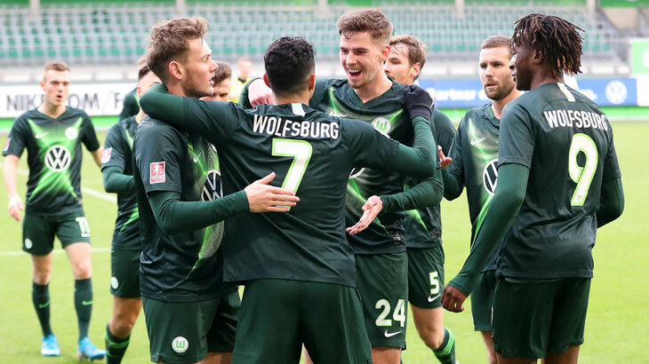 Die Spieler der U23 Mannschaft des VfL Wolfsburg liegen sich auf dem Platz jubelnd in den Armen.