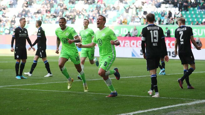 Lukas Nmecha, zweimaliger Torschütze heute und Kruse rennen nach dem Tor von Kruse gemeinsam jubelnd über das Spielfeld. Die Bielefelder laufen mit hängenden Köpfen vorbei.