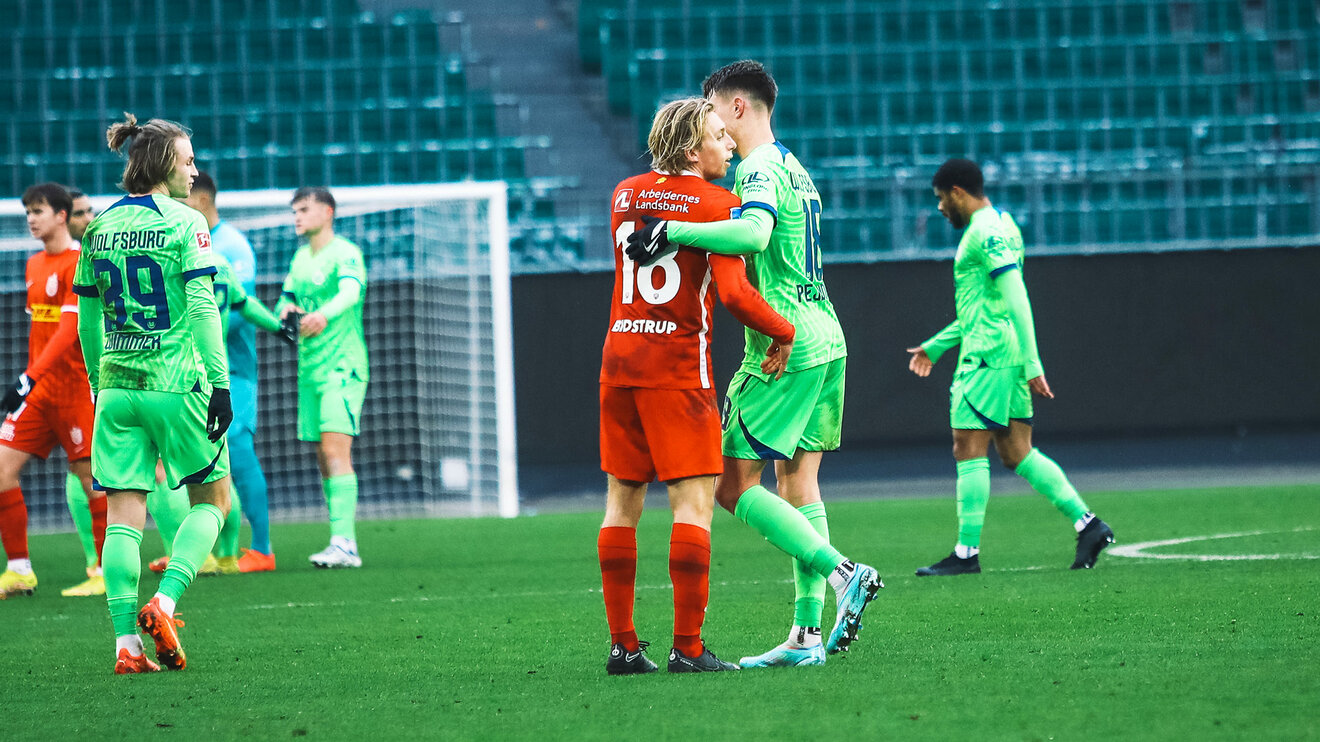 Ein VfL Wolfsburg Spieler umarmt einen Gegner.