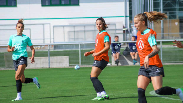 Spielerinnen Rauch und Oberdorf vom VfL Wolfsburg auf dem Trainingsplatz mit Laibchen.