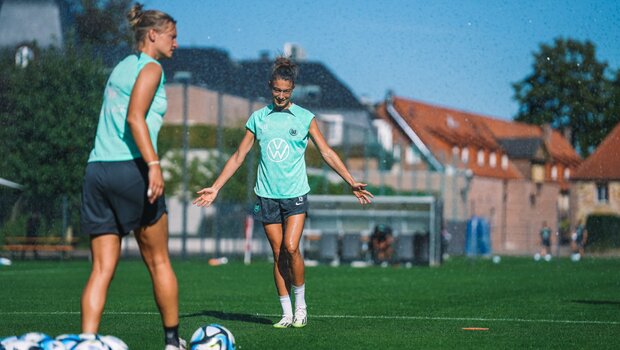 Alexandra Popp und Felicitas Rauch vom VfL Wolfsburg laufen über den Trainingsplatz.