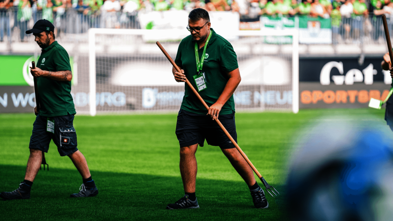 Aushilfen des VfL Wolfsburg bei der Pflege des Rasens.