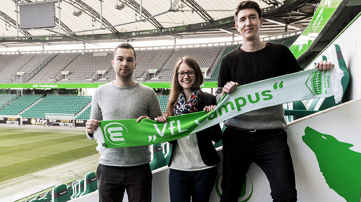 Die drei Stipendiaten halten einen VfL Wolfsburg-Schal hoch.